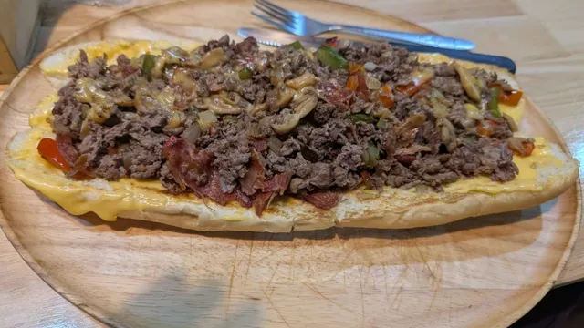 The Super 12" Ultimate at Mano's Cheesesteaks & Burgers in Pattaya - shaved beef, smokey bacon, mushrooms, bell peppers and onions topped with melted cheese on a 12-inch hoagie, served open-face on a wood platter