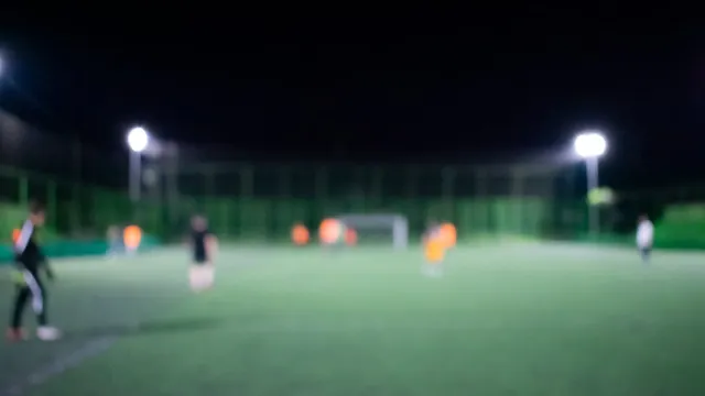 Football on a grass pitch under floodlights
