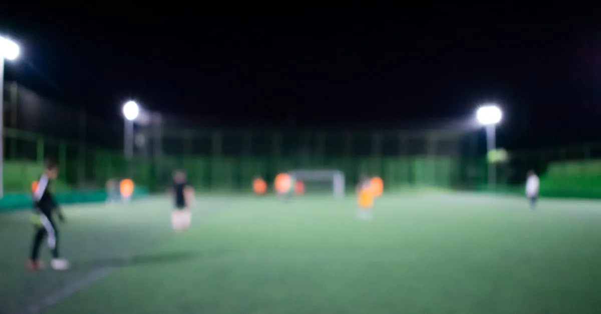 Football on a grass pitch under floodlights