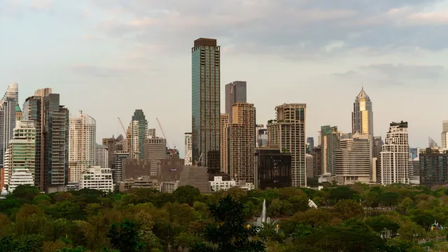 Bangkok's Sukhumvit skyline at dusk - modern high-rise towers lit against the evening sky, the kind of central district where Travelodge Sukhumvit 11 sits